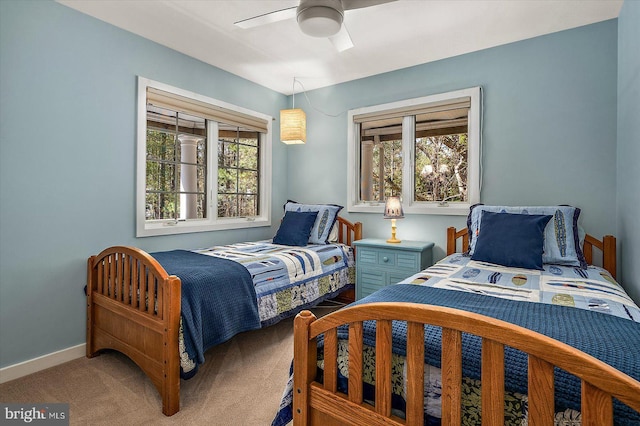 carpeted bedroom with a ceiling fan, baseboards, and multiple windows