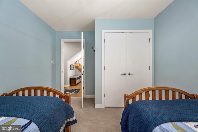 bedroom featuring baseboards, a closet, and light colored carpet