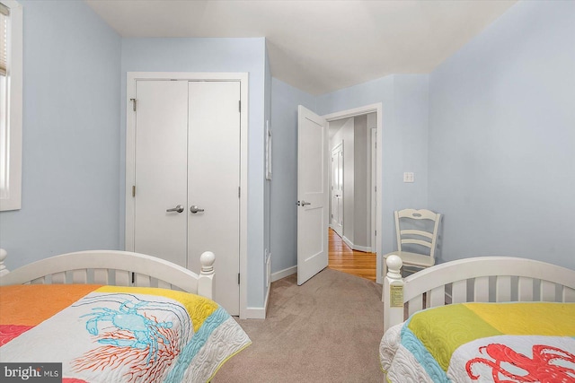 bedroom featuring baseboards, light carpet, and a closet