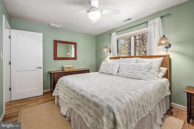 bedroom featuring baseboards, wood finished floors, and visible vents