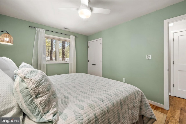 bedroom with light wood-type flooring, visible vents, a ceiling fan, and baseboards
