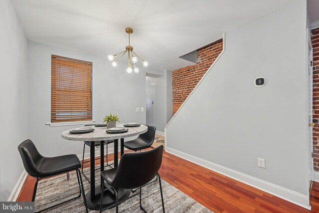 935 S Kenwood Ave, Baltimore, MD 21224 - dining space featuring wood finished floors, brick wall, baseboards, and a notable chandelier