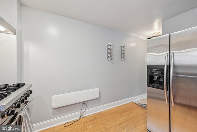 935 S Kenwood Ave, Baltimore, MD 21224 - kitchen with light wood-style floors, baseboards, stainless steel refrigerator with ice dispenser, and wall chimney exhaust hood