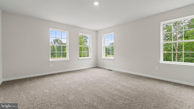 carpeted empty room with a healthy amount of sunlight, baseboards, and visible vents