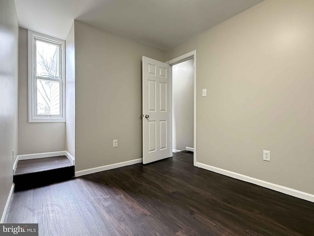 empty room featuring baseboards and dark wood-style floors
