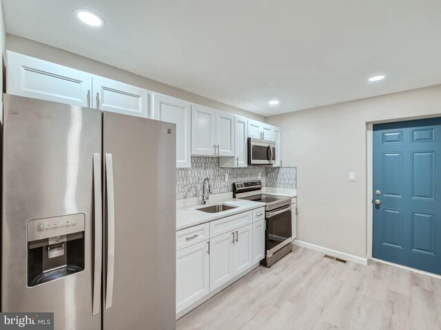 1324 W Pratt St, Baltimore, MD 21223 - kitchen with appliances with stainless steel finishes, light countertops, white cabinets, light wood-style floors, and recessed lighting