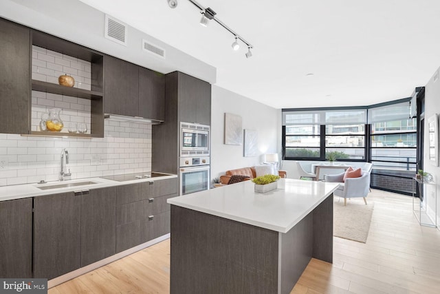 kitchen featuring open shelves, a sink, light countertops, appliances with stainless steel finishes, and visible vents