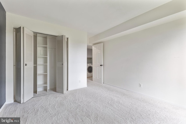 unfurnished bedroom featuring baseboards, carpet, a closet, and washer / clothes dryer