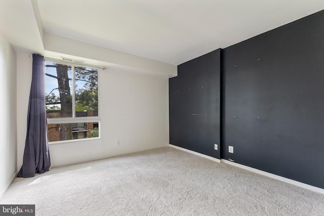 unfurnished room featuring carpet floors, visible vents, and baseboards
