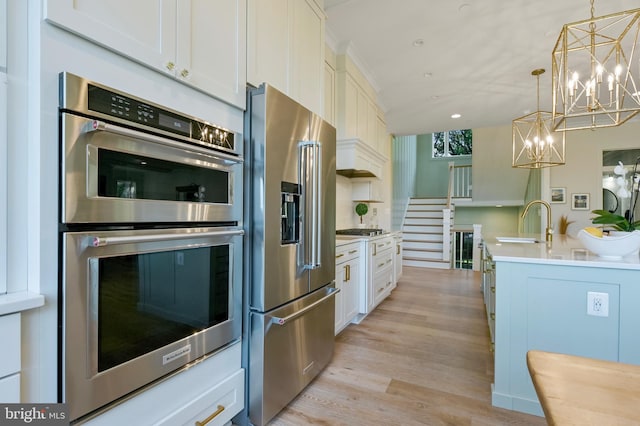 938A Benning Rd, Galesville, MD 20765 - kitchen featuring white cabinets, a notable chandelier, a sink, light wood-type flooring, and stainless steel appliances