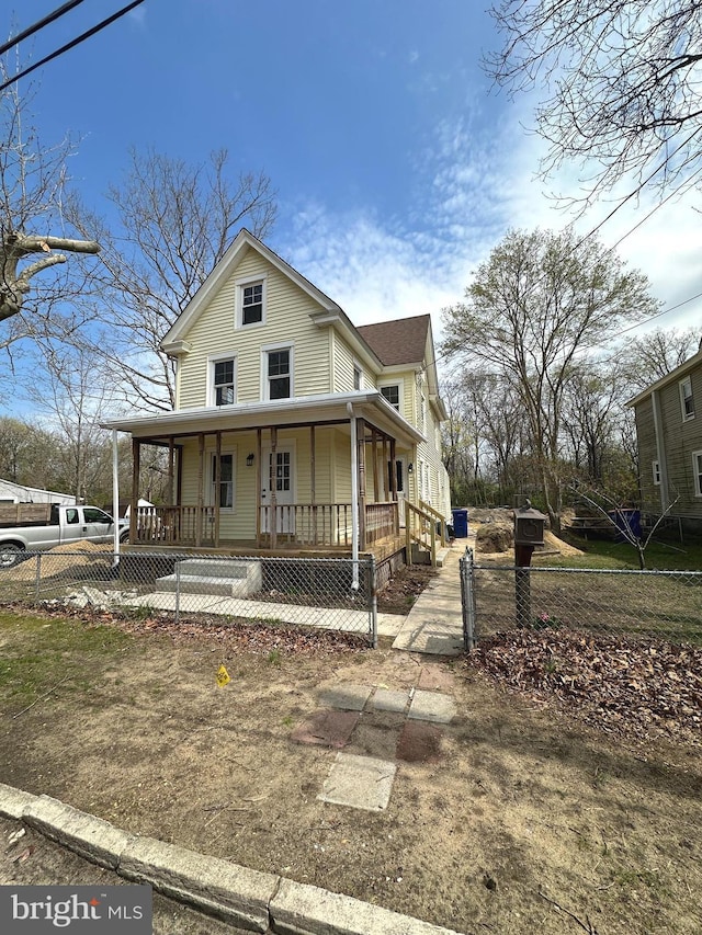 farmhouse featuring a fenced front yard and covered porch