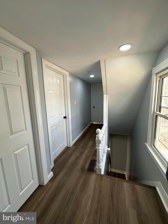 corridor featuring recessed lighting, lofted ceiling, dark wood-style floors, visible vents, and baseboards
