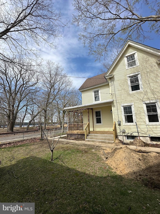 back of property with a yard and a porch