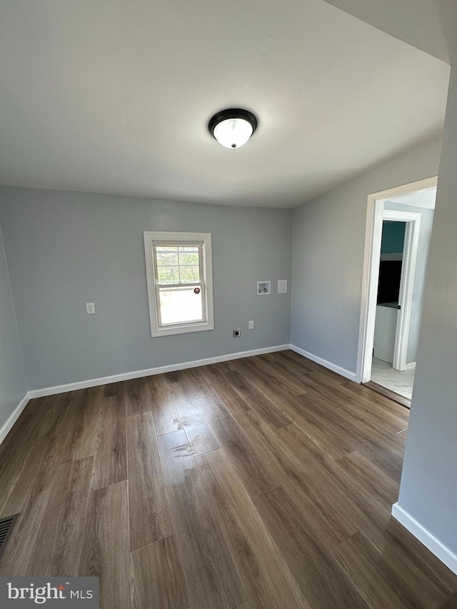 spare room with baseboards and dark wood-style flooring