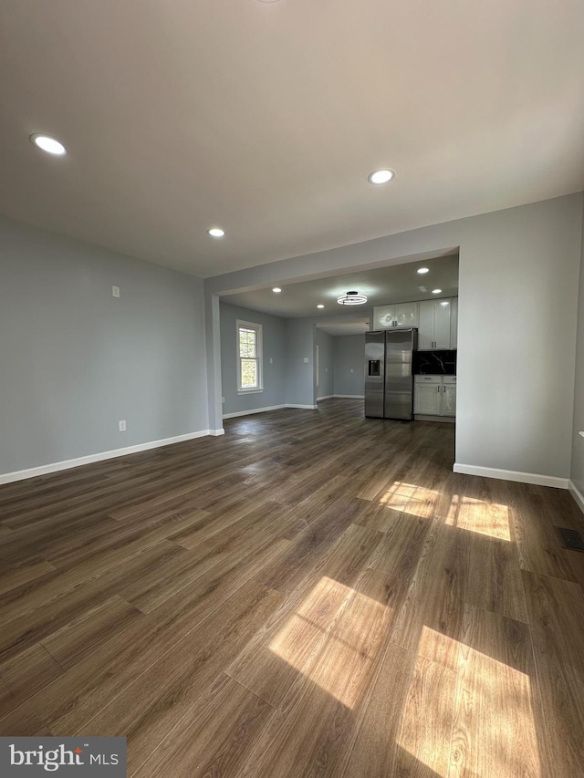 unfurnished living room featuring baseboards, recessed lighting, and dark wood finished floors