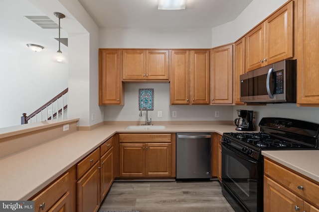 13945 Hollow Wind Way Unit 201, Woodbridge, VA 22191 - kitchen featuring a sink, light wood finished floors, light countertops, decorative light fixtures, and appliances with stainless steel finishes