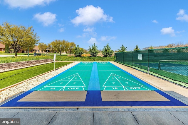 view of home's community with shuffleboard, a tennis court, and fence