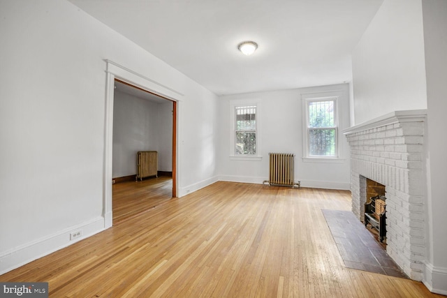 4516 13th St NW, Washington, DC 20011 - unfurnished living room featuring radiator, light wood-type flooring, a brick fireplace, and baseboards