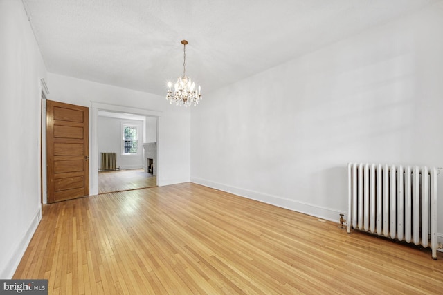4516 13th St NW, Washington, DC 20011 - spare room with radiator heating unit, light wood finished floors, a chandelier, and baseboards
