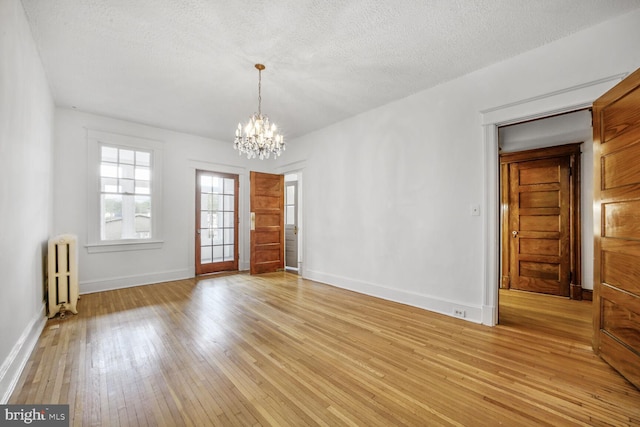 4516 13th St NW, Washington, DC 20011 - empty room featuring radiator heating unit, a chandelier, light wood-style floors, baseboards, and a textured ceiling