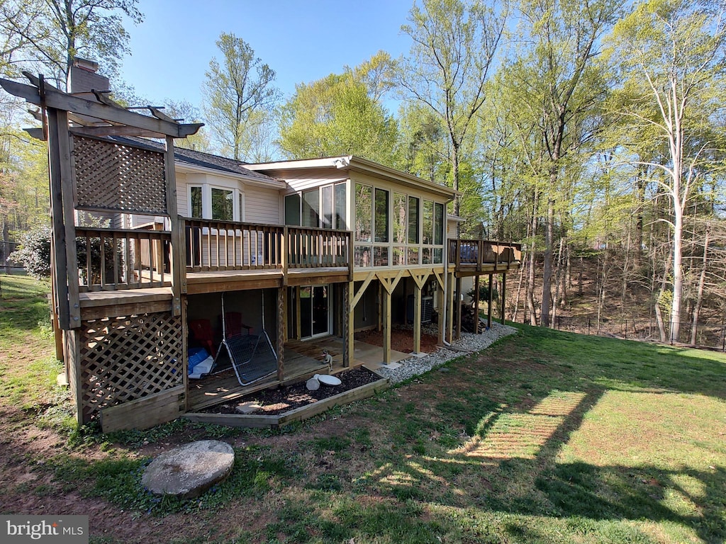 back of property with a deck and a lawn