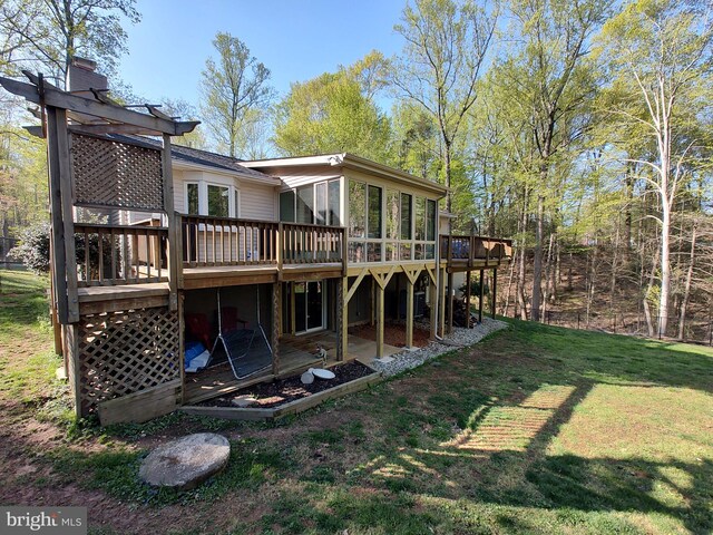 back of property with a deck and a lawn