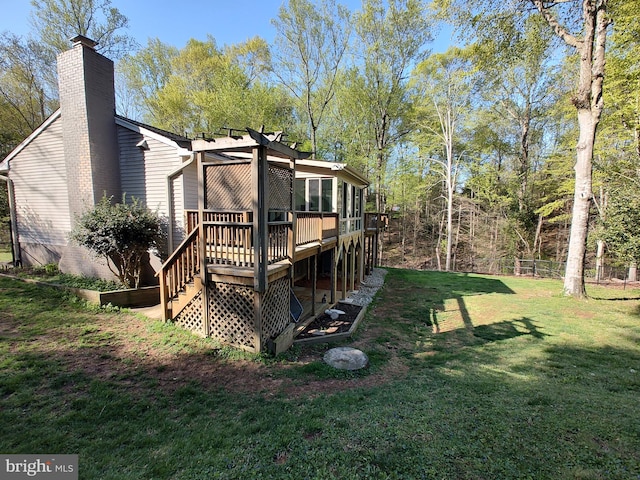 rear view of property with a chimney, fence, a deck, and a lawn