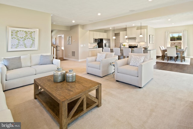 living room featuring light carpet, baseboards, visible vents, and recessed lighting