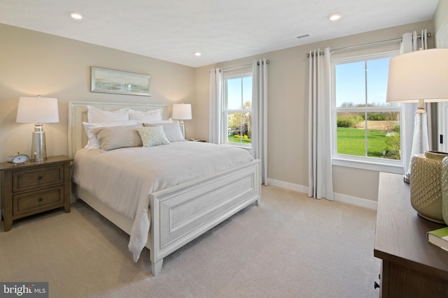 bedroom featuring multiple windows, light carpet, baseboards, and visible vents