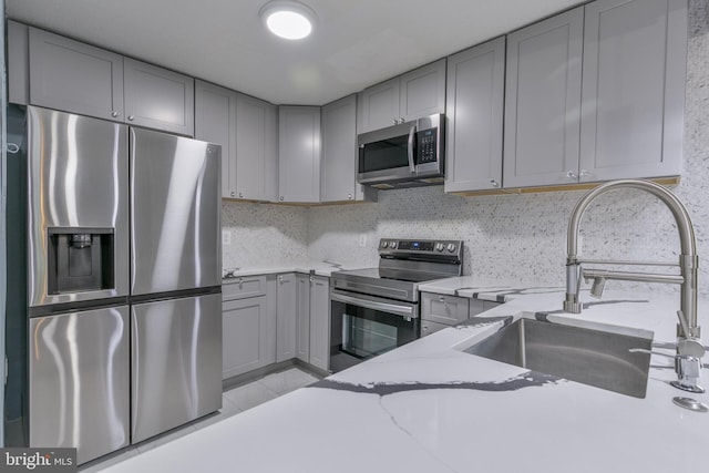 623 Center St Unit 101, Herndon, VA 20170 - kitchen featuring stainless steel appliances, gray cabinetry, light stone countertops, and backsplash