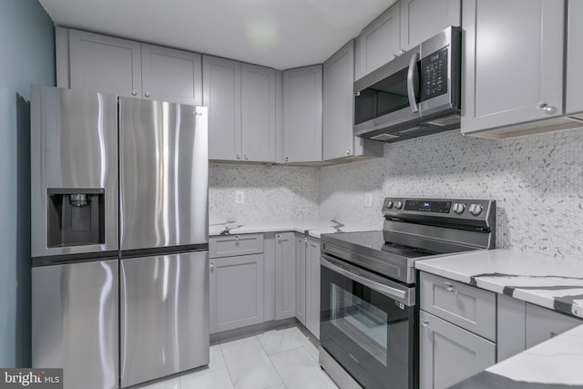 623 Center St Unit 101, Herndon, VA 20170 - kitchen featuring stainless steel appliances, gray cabinetry, backsplash, and light stone countertops