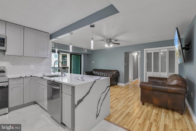 623 Center St Unit 101, Herndon, VA 20170 - kitchen with appliances with stainless steel finishes, open floor plan, gray cabinets, a peninsula, and light stone counters