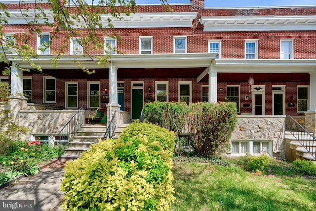 view of front of property featuring a porch, stairway, and brick siding