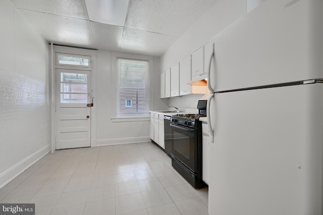 kitchen with baseboards, gas stove, white cabinetry, freestanding refrigerator, and dishwashing machine