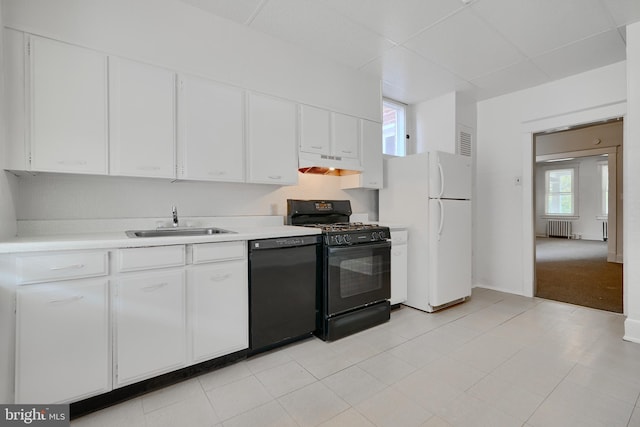 kitchen featuring light countertops, radiator heating unit, under cabinet range hood, black appliances, and a sink