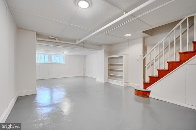 below grade area featuring stairs and baseboards