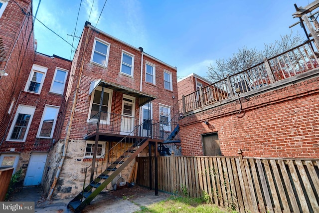 rear view of property featuring brick siding and stairs