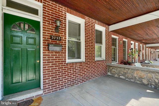 entrance to property with a porch and brick siding