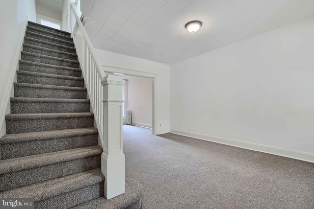 staircase featuring baseboards and carpet