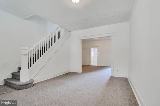 interior space featuring stairway, baseboards, crown molding, and carpet