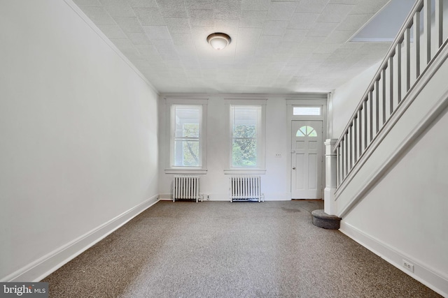 foyer featuring radiator heating unit, stairway, and baseboards