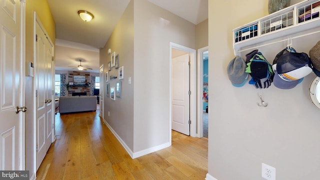 hall featuring light wood-style flooring and baseboards