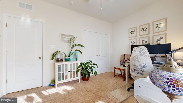 carpeted home office with ceiling fan and visible vents