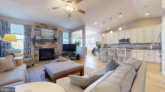 living room featuring light wood finished floors, plenty of natural light, vaulted ceiling, and ceiling fan