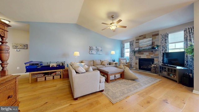 living area with lofted ceiling, a fireplace, light wood-style floors, and ceiling fan