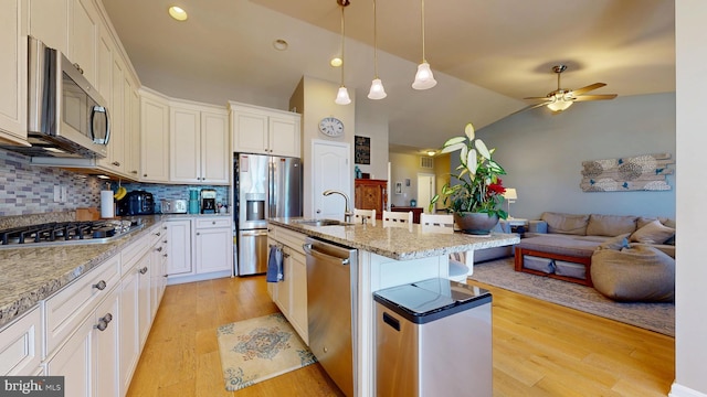 kitchen with stainless steel appliances, a ceiling fan, a sink, decorative backsplash, and open floor plan