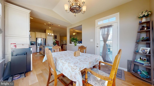 dining space featuring an inviting chandelier, lofted ceiling, and light wood-style flooring