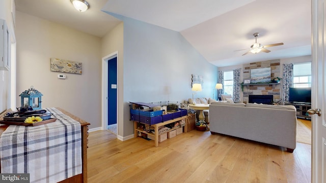 living room with a fireplace, a healthy amount of sunlight, a ceiling fan, and light wood-type flooring
