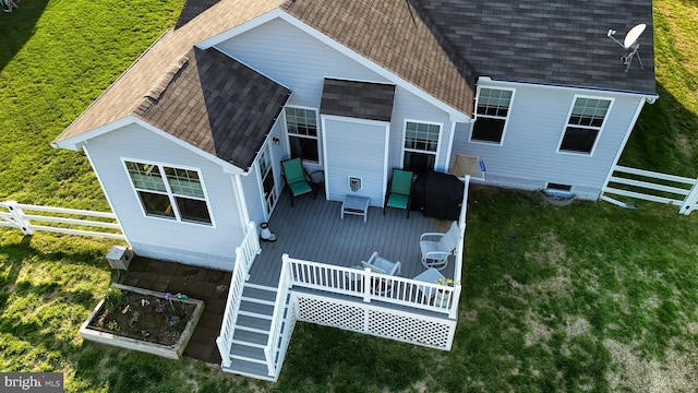exterior space with a wooden deck, fence, a yard, and a shingled roof