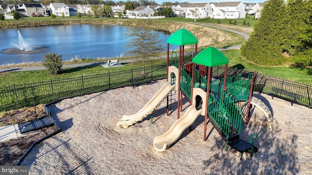 community playground featuring fence, a residential view, and a water view